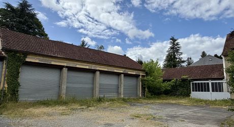 En plein centre de Montignac-Lascaux, ensemble comprenant une maison et d'importants bâtiments à destination d'atelier/stockage, avec cour et jardin.